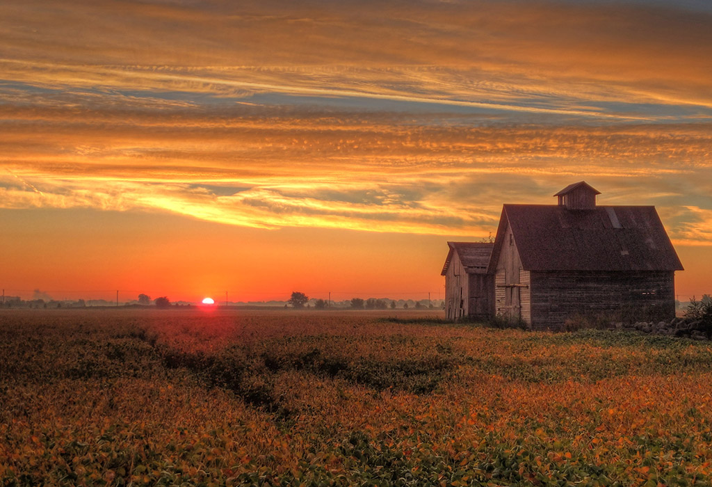 Orange sunrise lights up sky behind barn on the 2nd Day of Fall.